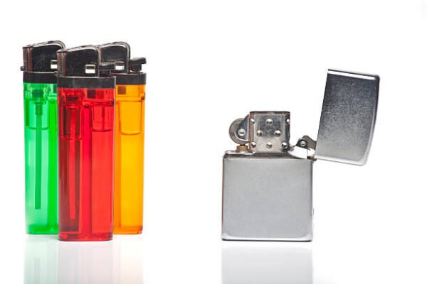 Colorful disposable lighters next to a metal flip-top lighter on a white background.