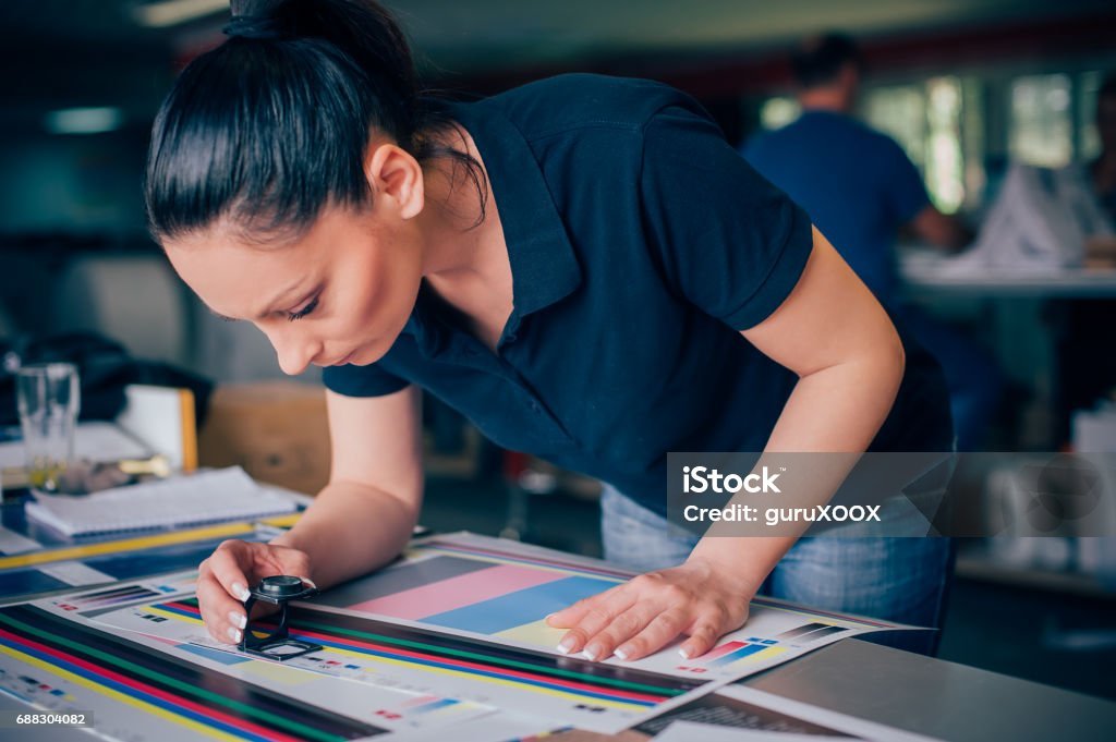 "Female print quality control inspector examining color samples closely in a printing facility."