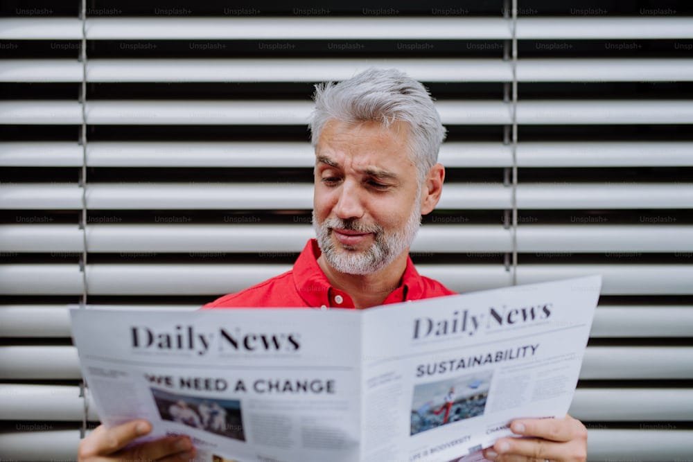 Middle-aged man reading a newspaper with a focused expression.