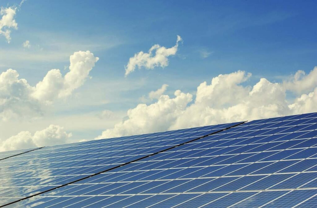 Solar panels under a bright blue sky with clouds.