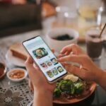 Person using a mobile app to browse food delivery options during a meal."