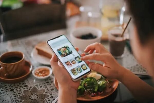 Person using a mobile app to browse food delivery options during a meal."