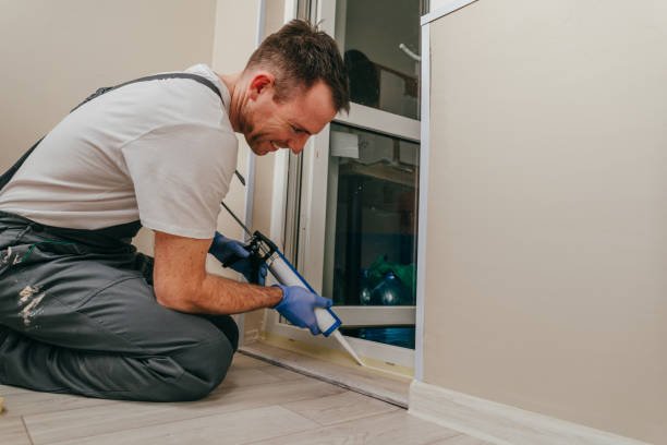 "Worker applying sealant to a door frame during installation"