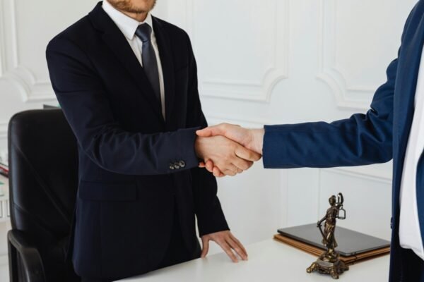 "Business professionals in formal suits shaking hands, symbolizing a successful agreement or partnership"