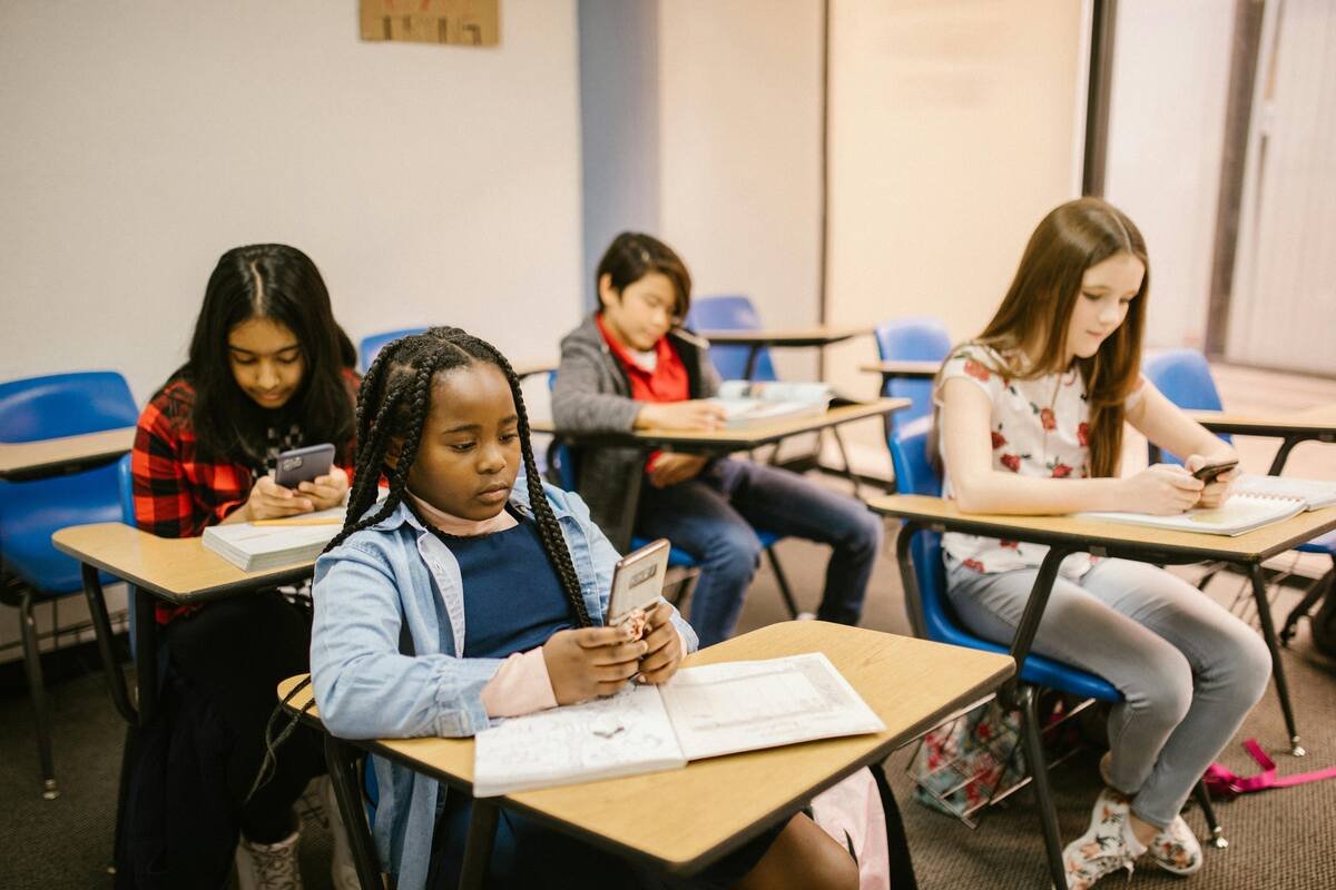 Students in a classroom using smartphones and books for learning