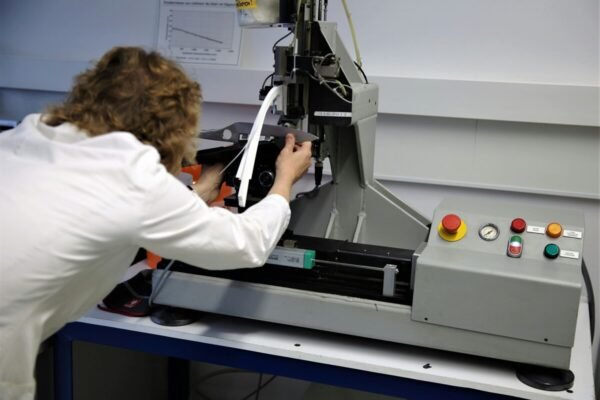 Scientist in a white lab coat operating an industrial testing machine in a laboratoryScientist in a white lab coat operating an industrial testing machine in a laboratory