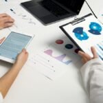 "Business professionals analyzing data charts and reports on a digital tablet and clipboard in a meeting.