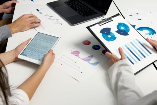 "Business professionals analyzing data charts and reports on a digital tablet and clipboard in a meeting.