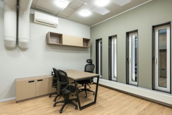 Modern office space with ergonomic chairs, wooden table, and stylish decor."