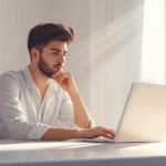 A focused professional working on a laptop in a bright modern office, showcasing innovation and productivity at renas tech.